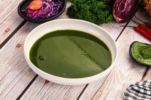 A bowl of green soup on a table photo