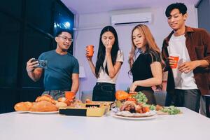 Three young people standing around a table with food photo