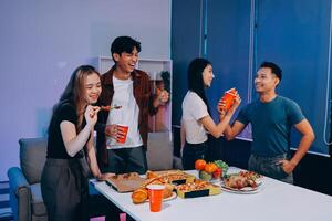 Four friends eating pizza and drinking soda at a table photo