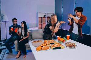 A group of people sitting around a table with pizza and drinks photo