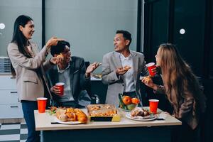 Group of people eating pizza and drinks in office photo