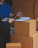 A man and woman standing in front of boxes with a tablet photo