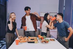 Four friends eating pizza and drinking beer at a table photo