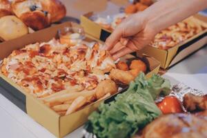 A person taking a piece of pizza from a box photo