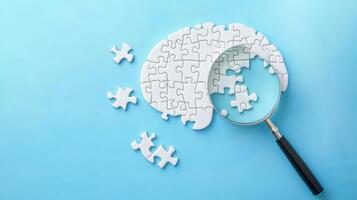 Solving a puzzle with a magnifying glass reveals pieces scattered around a brain-shaped arrangement on a light blue background photo