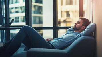 Man relaxing in a modern apartment with large windows overlooking a city skyline during sunset hours photo