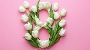 A beautiful decorative arrangement featuring delicate white tulips gracefully shaped into the number eight against a soft pink background photo