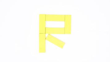 Isolated letter R from yellow color wood block on white background photo