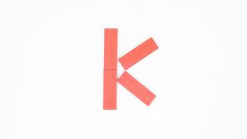 Letter K from red color wood block isolated on white background photo