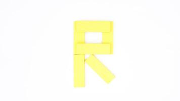 Yellow color wood block formed into letter R isolated on white background photo
