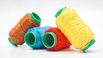 Light blue, yellow, red, and brown spool of sewing thread isolated on white background photo
