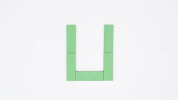 Letter U from green color wood block isolated on white background photo