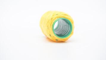 Close up yellow spool of sewing thread isolated on white background photo