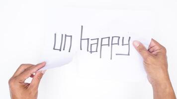 Man hands tearing letters UN from word UNHAPPY isolated on white background photo