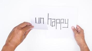 Close up of male hands tearing letters UN from word UNHAPPY isolated on white background photo