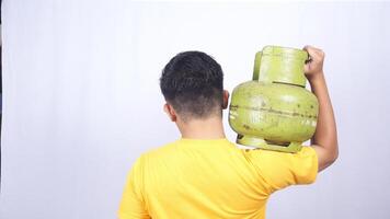 Rear view of Asian man carrying Indonesia 3kg green LPG gas cylinder on his shoulder isolated on white background photo