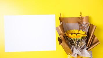 Fake single sunflower in bouquet made from craft paper with blank paper for copy space isolated on yellow background photo