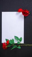Artificial stalk of red roses with blank paper for copy space isolated on black background photo