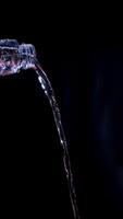 Water is poured from bottle isolated on black background photo