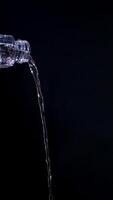 Poured water from bottle isolated on black background photo