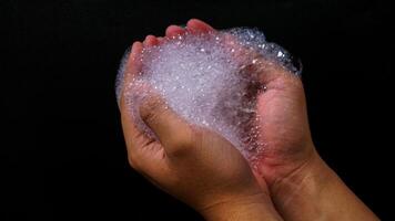 Bubbles foam in hands isolated on black background photo
