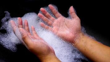 Hands with bubbles foam isolated on black background photo