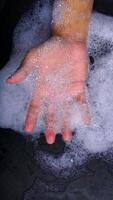 Close up of hand with many bubble foam isolated on black background photo