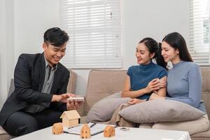 Technology in real estate. A real estate agent shows property details on a digital device to two clients in a lively setting. photo