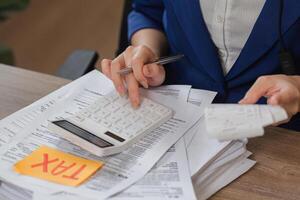 Tax Calculation Process. Individual using a calculator and reviewing tax-related documents for accurate filing. photo