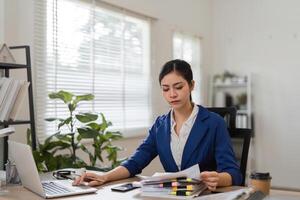 Financial documentation and analysis. Business professional organizing papers and working on a laptop in the office. photo