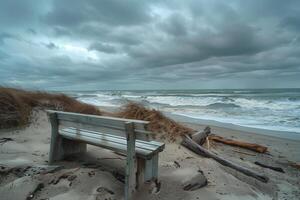 A bench sitting on a sandy beach with a stormy sky photo