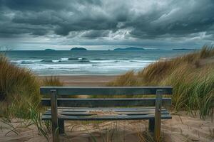 A bench sitting on a beach with a stormy sky photo