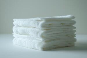 A stack of white towels on a white surface photo