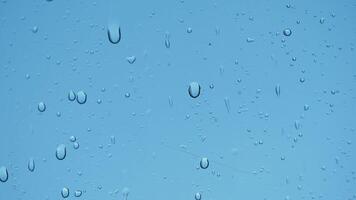 Raindrops create patterns on a clear glass surface in daylight video