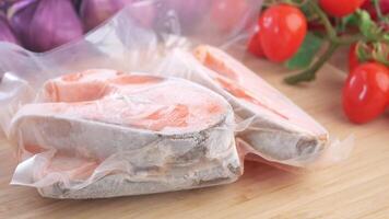 Preparing frozen salmon with fresh tomatoes on a wooden surface video