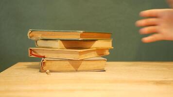 Stacked old books on a wooden surface with a plain background video
