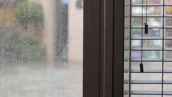 Rain pours outside while blinds filter light through window video
