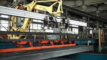 A large automated robot manipulator unloads heavy steel parts from a conveyor line. Automation in heavy industry. video