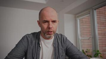 A middle-aged man sits at home, visibly crying and looking deeply sad. He appears to be struggling with problems and depression, conveying a powerful sense of sorrow and despair in an intimate video