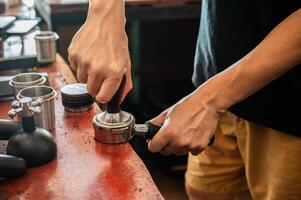 Barista using a tamper to press ground coffee into a portafilter. photo