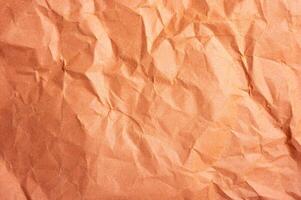 Full frame shot of crumpled orange colour paper sheet texture and background. photo