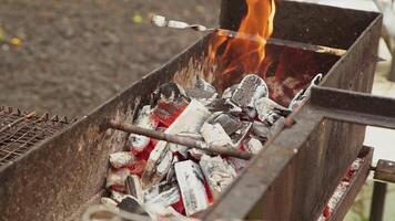 Coals are burning in large iron barbecue. Fire burns between hot pieces of wood. There is empty skewer. Brazier ignition. video
