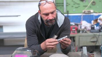 A blacksmith reflects on the realization of a job, he analyzes a metal bar until he thinks he has found the solution. He heads towards the tool bench. Solution thinking concept. video