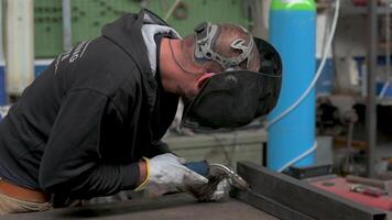 Safety at work, a blacksmith, before welding, wears a protective mask and work gloves. He positions the welding machine on the point to be welded and activates it, creating glare, sparks and smoke. video
