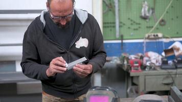 A blacksmith reflects on the creation of a job, he analyzes a metal bar by measuring it with an instrument, evaluating the possible solutions. Solution thinking concept. video