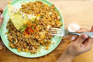 Seen from above, an unrecognizable person's hand with a fork about to eat a Peruvian dish called arroz chaufa. photo