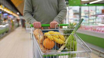 Man pushing shopping cart in grocery store aisle video