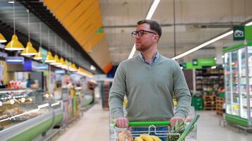 Man pushing shopping cart in grocery store aisle video