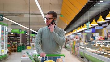 Man talking on phone while grocery shopping in supermarket video