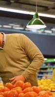 Man selecting grapefruit, pineapple, and bananas in supermarket video